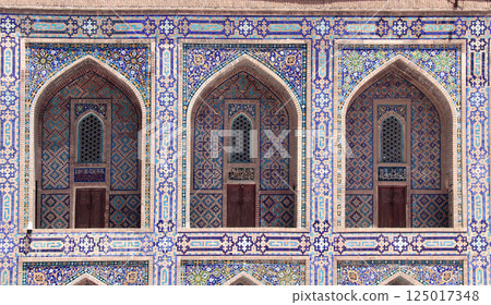 Famous landmark - Ulugh Beg Madrasah on Registan square, Samarkand, Uzbekistan. Arches with tile ornament in the courtyard of Ulugh Beg Madrasa. Text on the wall is a quote from the Quran Famous landmark - Ulugh Beg Madrasah on Registan square, Samarkand, Uzbekistan. Arches with tile ornament in the courtyard of Ulugh Beg Madrasa. Text on the wall is a quote from the Quran 125017348