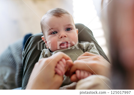 Portrait of baby boy on his father's lap. 125017997