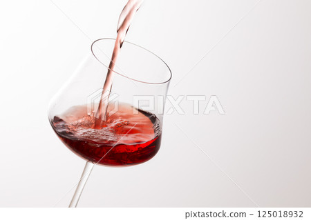 Pour the red wine into the glass 125018932