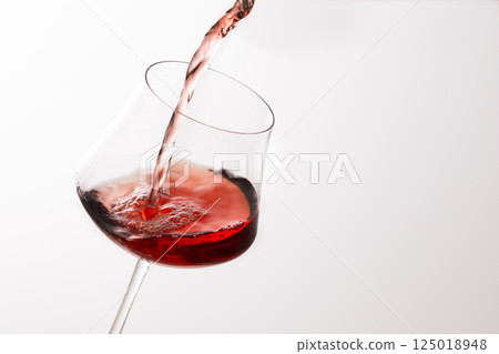 Pour the red wine into the glass 125018948