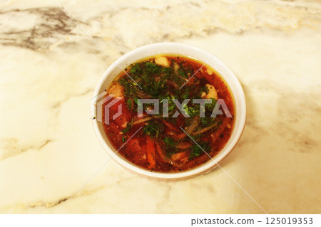 Red borscht with greenery on a light background close-up. National food 125019353