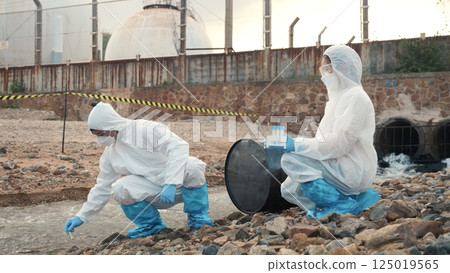 Ecologist sampling water from the river with test tube, Scientist or Biologist in a protective suit and protect mask collects sample of waste water from industrial for analyze, problem environment Ecologist sampling water from the river with test tube, Scientist or Biologist in a protective suit and protect mask collects sample of waste water from industrial for analyze, problem environment 125019565