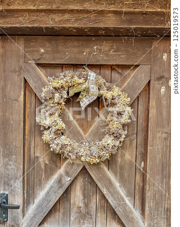 Vintage wooden door decorated with rustic dried flower wreath and bow. High quality photo 125019573