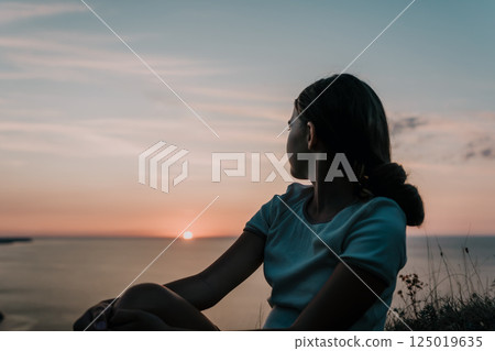 Silhouette of a Woman Watching the Sunset Silhouette of a Woman Watching the Sunset 125019635