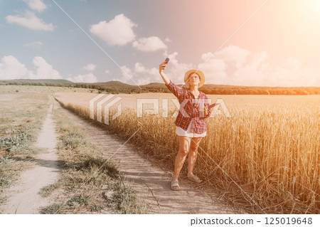 Woman wheat field. Agronomist, Woman farmer check golden ripe barley spikes in cultivated field. Closeup of female hand on plantation in agricultural crop management concept. Slow motion 125019648