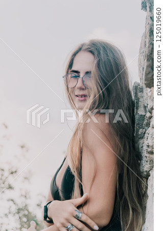 Woman Glasses Beach Portrait: A woman wearing glasses poses while leaning against a rock on the beach. 125019660
