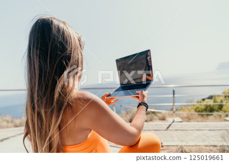 Woman with Laptop Relaxing by the Ocean 125019661