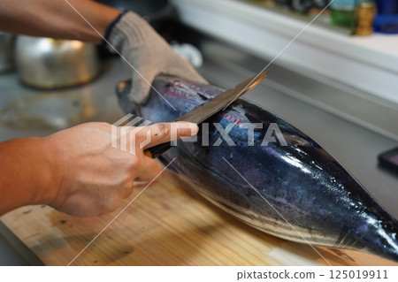 A man's hands cutting a fish 125019911