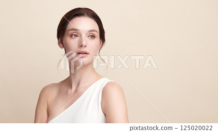 A beautiful young woman with clean, fresh skin against a beige background. Skincare, facial treatment, cosmetology, beauty, and spa. An elegant portrait of an woman. A beautiful young woman with clean, fresh skin against a beige background. Skincare, facial treatment, cosmetology, beauty, and spa. An elegant portrait of an woman. 125020022