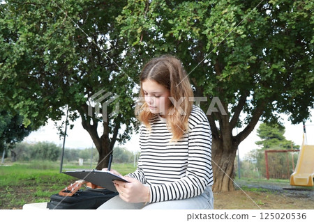 Girl Writes Musical Notes On A Sheet Music To Play Them With The Ukulele Girl Writes Musical Notes On A Sheet Music To Play Them With The Ukulele 125020536