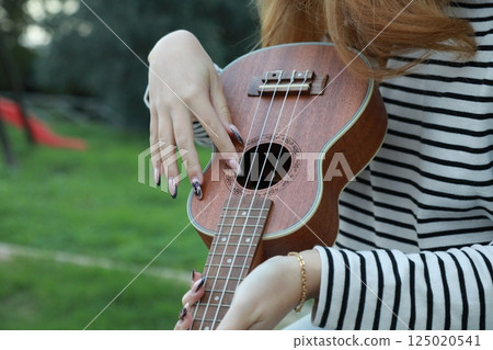 Artist Girl Plays Ukulele Musical Instrument Outside In Park 125020541