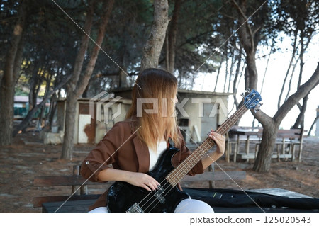 Girl Plays The Bass Instrument In The Countryside In Summer 125020543