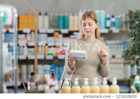 Girl in winter clothes looking for medicine in pharmacy 125020630
