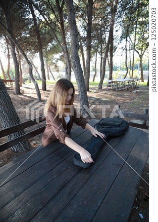 Girl Walks With Guitar Bass Instrument Case Behind Her In The Park Girl Walks With Guitar Bass Instrument Case Behind Her In The Park 125020703