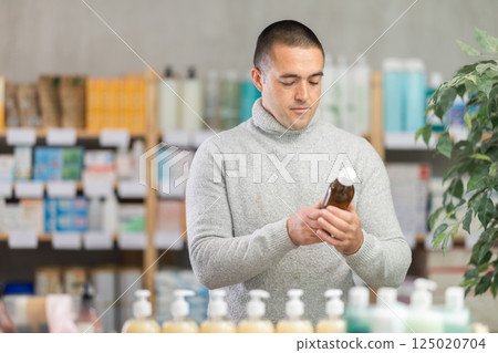 Young man chooses syrup at pharmacy Young man chooses syrup at pharmacy 125020704