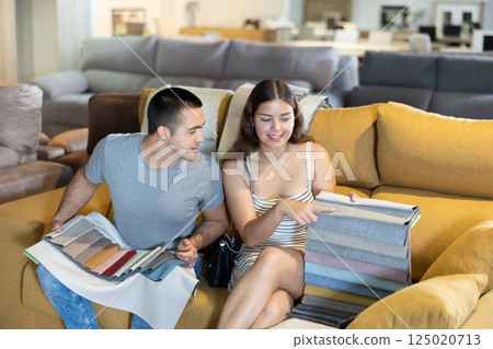 Smiling couple is choosing modern materials for furniture for their home in store 125020713