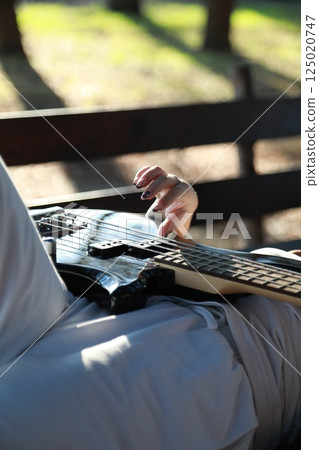 Girl Plays Bass Musical Instrument Lying On Table In Mountains 125020747