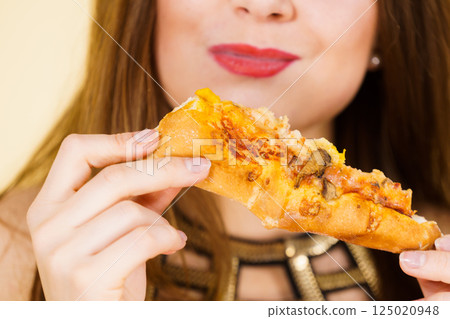 Woman eating hot pizza slice 125020948