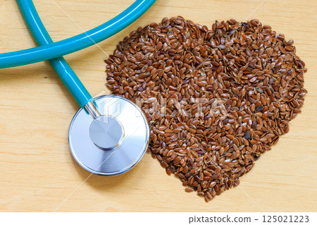 Raw flax seeds heart shaped and stethoscope Raw flax seeds heart shaped and stethoscope 125021223