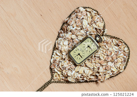 Oat flakes cereal heart shaped on wooden surface. Oat flakes cereal heart shaped on wooden surface. 125021224