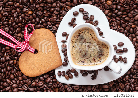 Heart shaped cup and cookie on coffee beans background Heart shaped cup and cookie on coffee beans background 125021555
