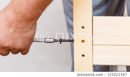 Assembling wood furniture using scredriver. DIY. 125021567