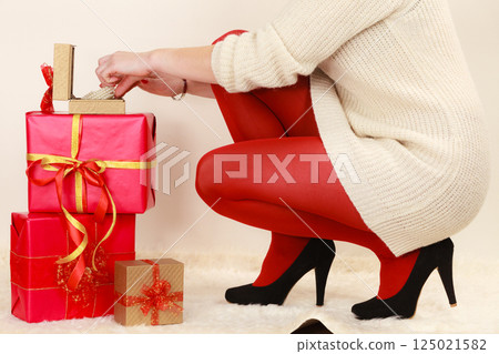 Woman with many gift boxes opening golden box with jewel pearls 125021582