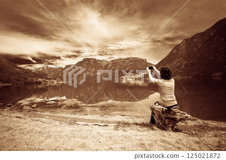 Tourist taking photo at norwegian fjord Tourist taking photo at norwegian fjord 125021872