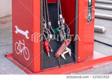 Close-up of bike repair station tools including wrenches and screwdrivers on red urban fixture 125021910