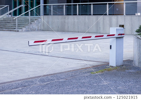 Lowered automatic parking barrier gate at office building entrance on paved driveway surface Lowered automatic parking barrier gate at office building entrance on paved driveway surface 125021915