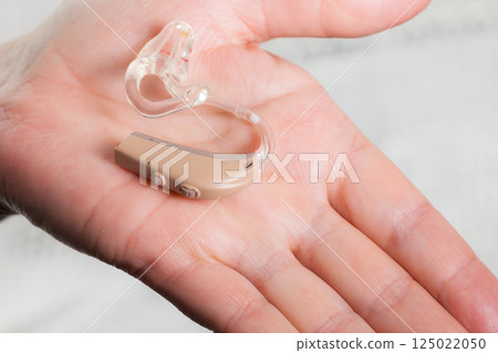 senior person holding hearing aid closeup 125022050