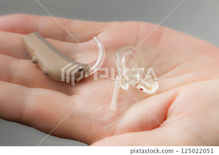 senior person holding hearing aid closeup 125022051