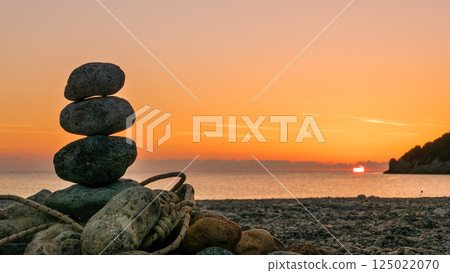 stone stack fireplace with rope on beach at sunrise stone stack fireplace with rope on beach at sunrise 125022070
