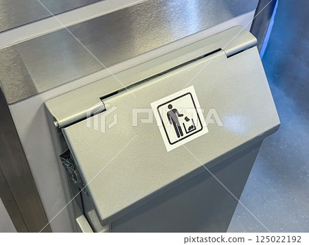 Close-up of modern stainless steel trash bin with waste disposal symbol in indoor public space, emphasizing cleanliness and hygiene Close-up of modern stainless steel trash bin with waste disposal symbol in indoor public space, emphasizing cleanliness and hygiene 125022192