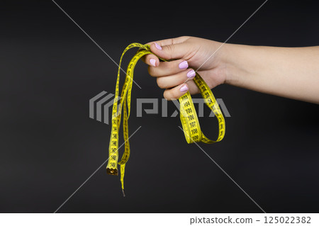 measuring tape centimeter in hand on dark background 125022382