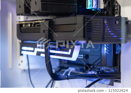 Close-up of GeForce RTX graphics card supported by illuminated RGB bracket inside modern custom-built gaming PC case 125022624