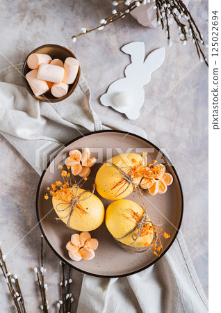 Easter eggs decorated with dried flowers and marshmallows on a plate top and vertical view 125022694