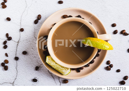 Close up of cold coffee with lime wedges in a cup on the table top view 125022710