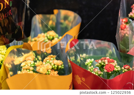 Closeup of blooming kalanchoe flowers in colorful plastic wrapping on store shelf with vibrant petals and fresh green buds in floral department 125022936