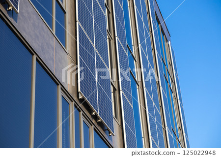 Solar panels installed on tall modern building reflecting clear blue sky renewable energy and sustainable urban architecture background Solar panels installed on tall modern building reflecting clear blue sky renewable energy and sustainable urban architecture background 125022948