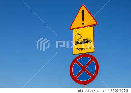 Warning road signs with exclamation mark, tram and car crash symbol, and no stopping traffic sign under clear blue sky Warning road signs with exclamation mark, tram and car crash symbol, and no stopping traffic sign under clear blue sky 125023076