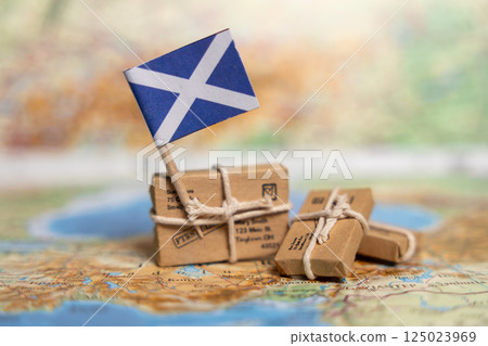 International Shipping and Delivery Services to Scotland: Small Packages with Scottish Flag on Vintage Map Background 125023969