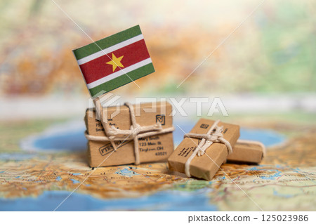International Shipping and Delivery Services to Suriname: Small Packages on World Map with National Flag Shows Global Mail Transport 125023986