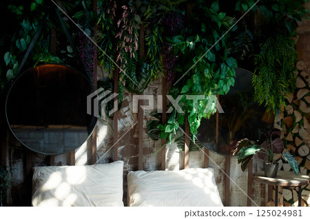 Ethnic-style headboard with mirrors and greenery. Spots of light on the wall. Honeymoon in a hot country 125024981