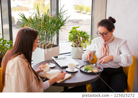 Young marketers structure a content funnel while enjoying cafe atmosphere. Concept of lead nurturing and online communication. Young marketers structure a content funnel while enjoying cafe atmosphere. Concept of lead nurturing and online communication. 125025272