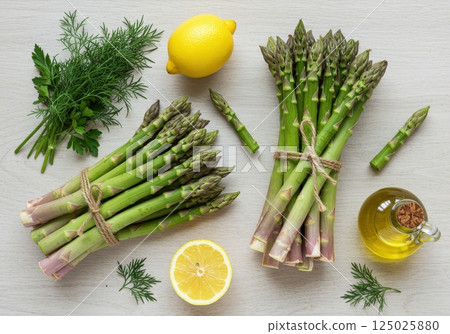 Fresh spring asparagus arranged with herbs and lemon on a light wooden surface Fresh spring asparagus arranged with herbs and lemon on a light wooden surface 125025880