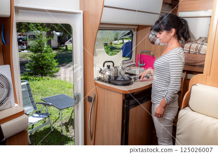 Woman cooking in camper, motorhome interior RV 125026007