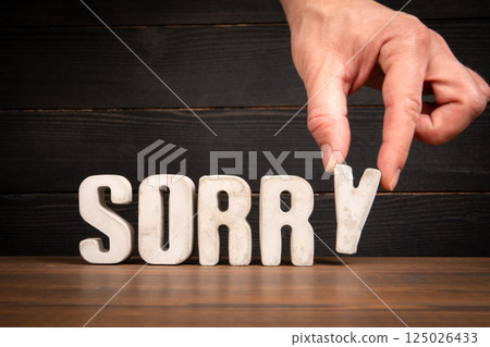 Hand Placing SORRY Text on Wooden Desk Hand Placing SORRY Text on Wooden Desk 125026433