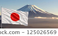 A close-up of the developing flag of Japan against the background of Mount Fuji, illuminated by the rays of the rising sun. 125026569