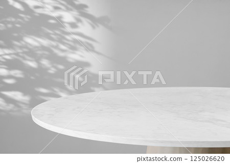 Round marble table top with tree leaves shadow drop on white wall background for mockup product display 125026620